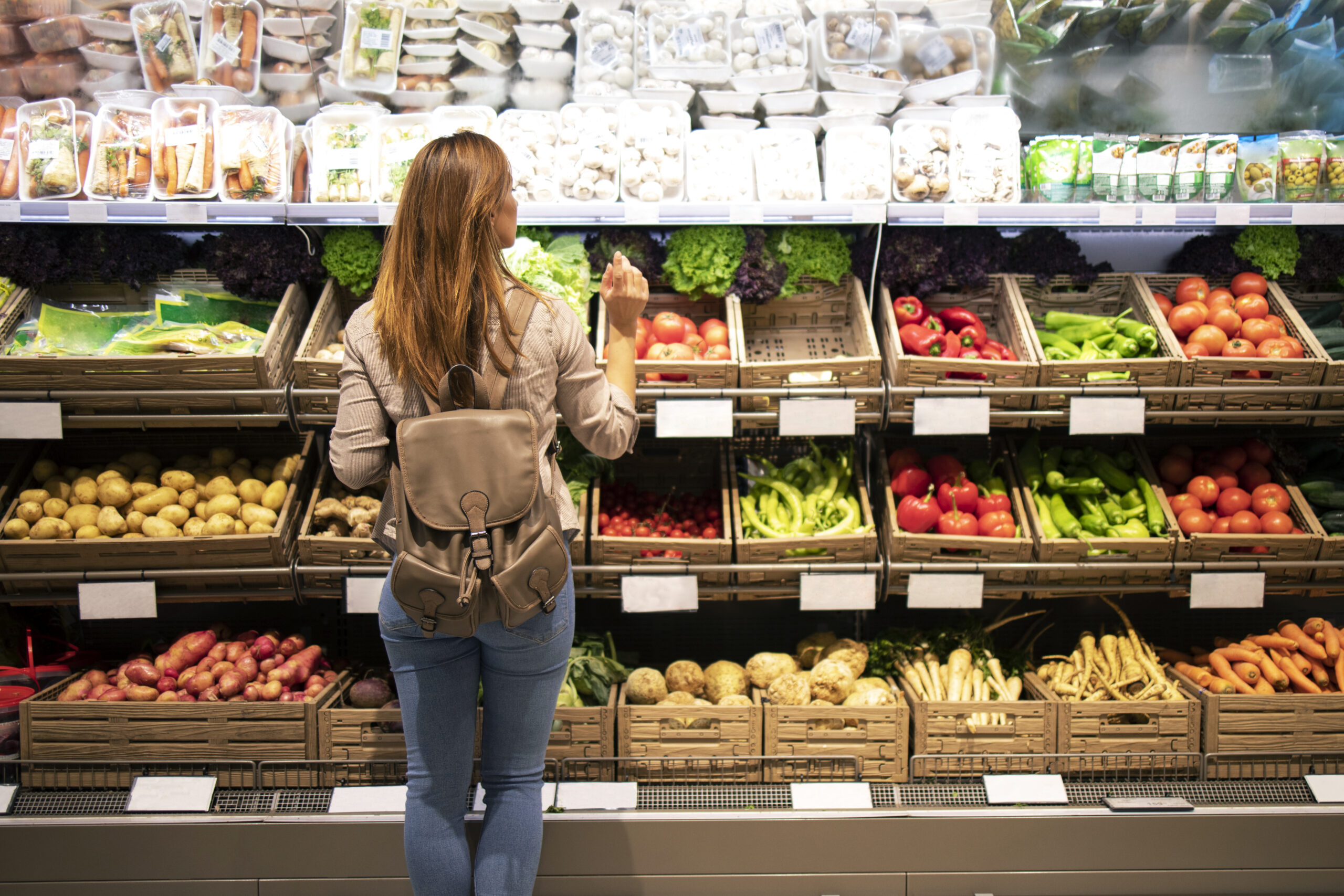 good looking woman standing front vegetable shelves choosing what buy scaled Warnbro Grocery Store 7 The Local Safety Bay Grocery Store Supporting Local Farmers